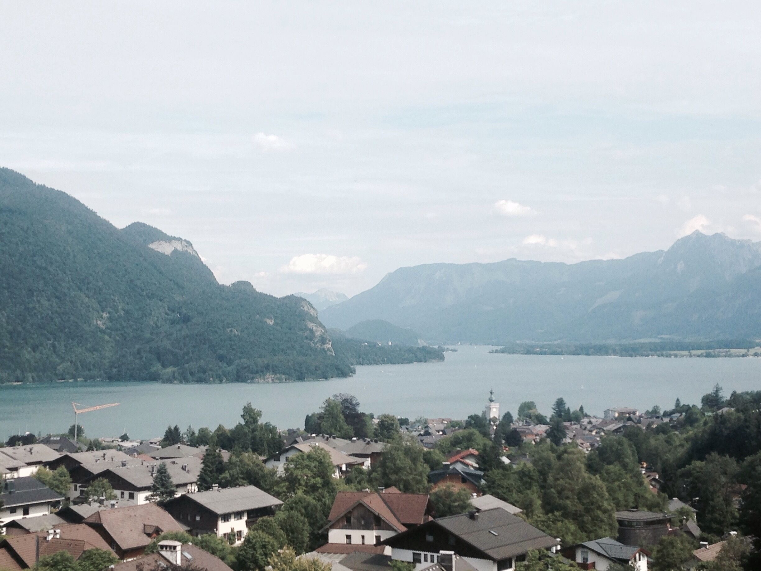 A lake surrounded by mountains and a residential area with houses.