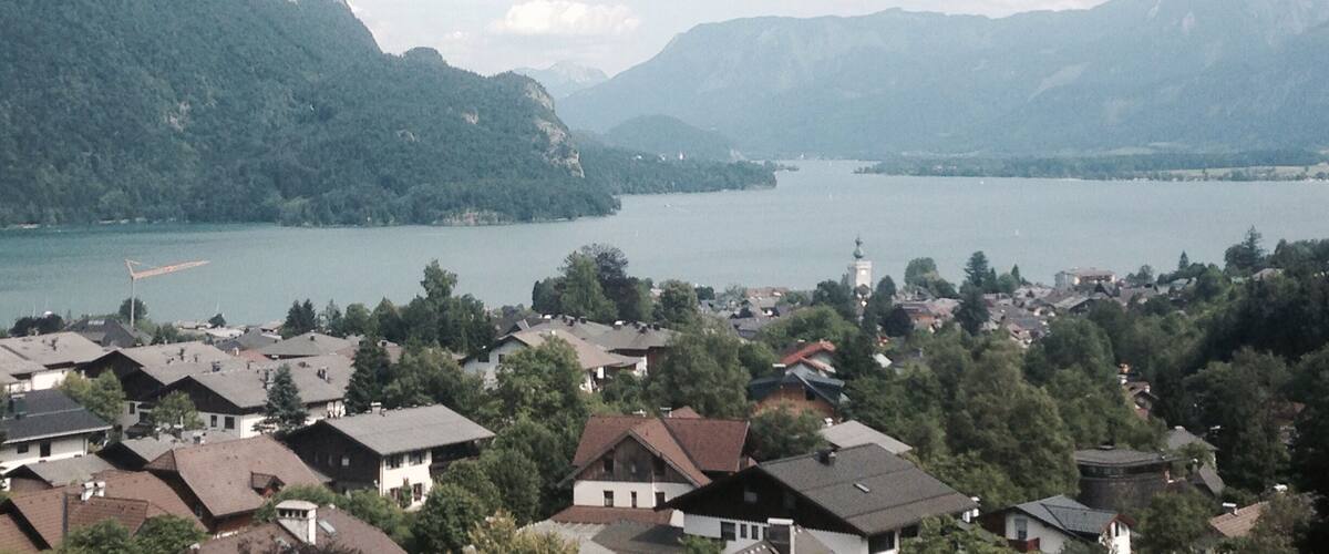 A lake surrounded by mountains and a residential area with houses.