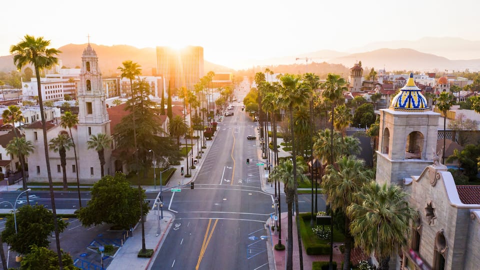 A cityscape with a prominent church, palm trees, and a clear sky.
