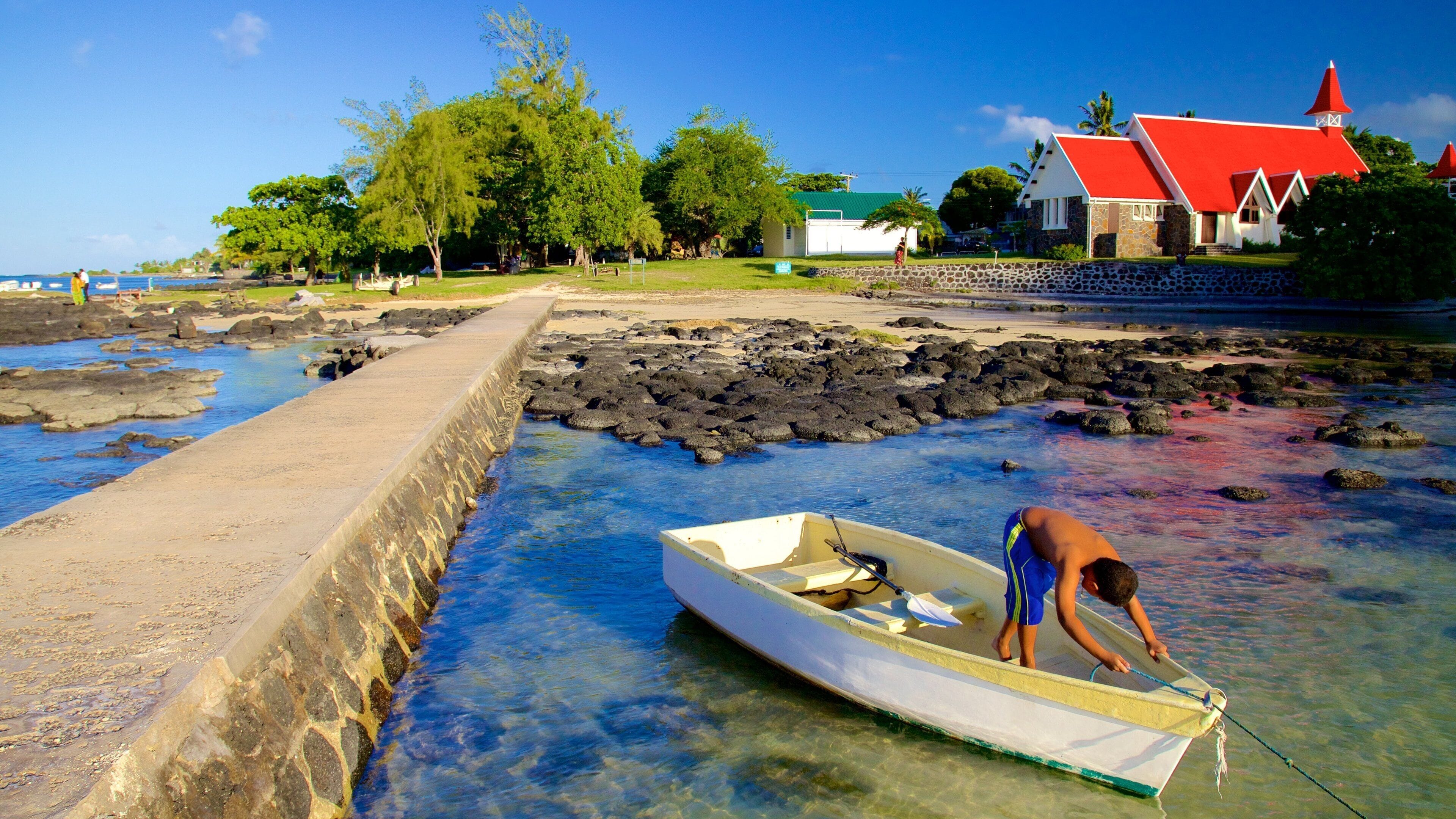 Cap Malheureux ofreciendo costa rocosa y una bahía o puerto y también un niño