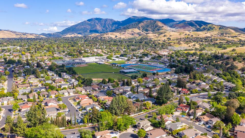 A residential area with houses, roads, and a large sports field.