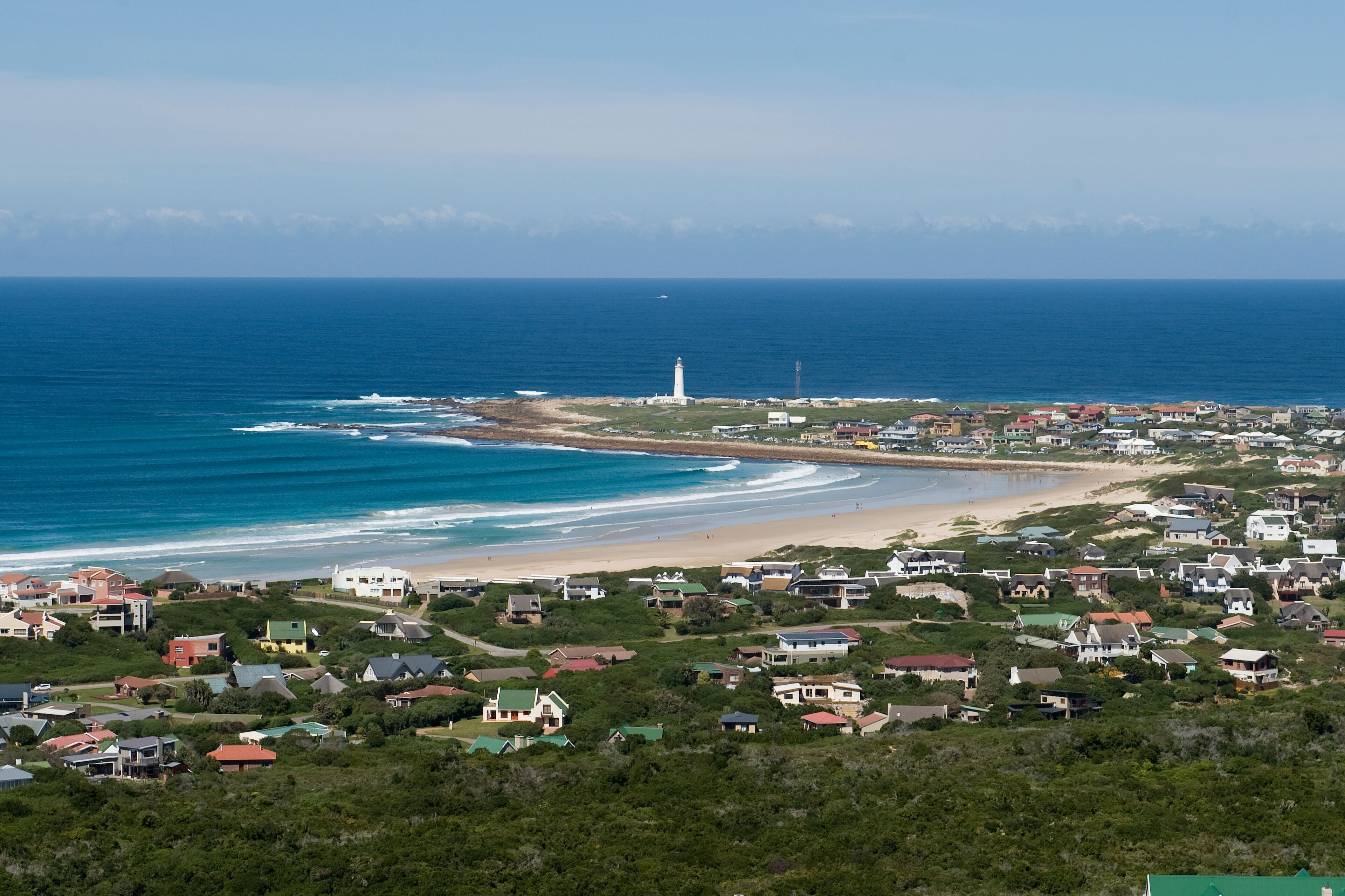 A coastal town with a lighthouse, beach, and residential area.