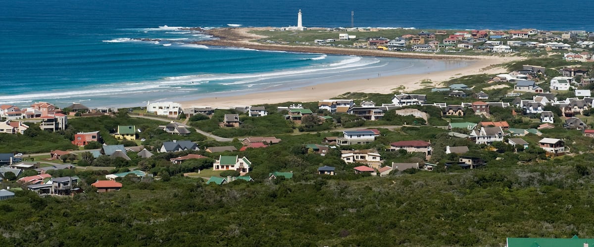A coastal town with a lighthouse, beach, and residential area.
