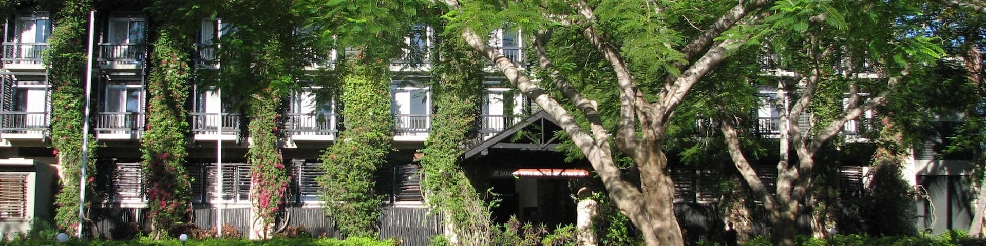 A building with multiple balconies, surrounded by lush greenery and a well-maintained lawn.