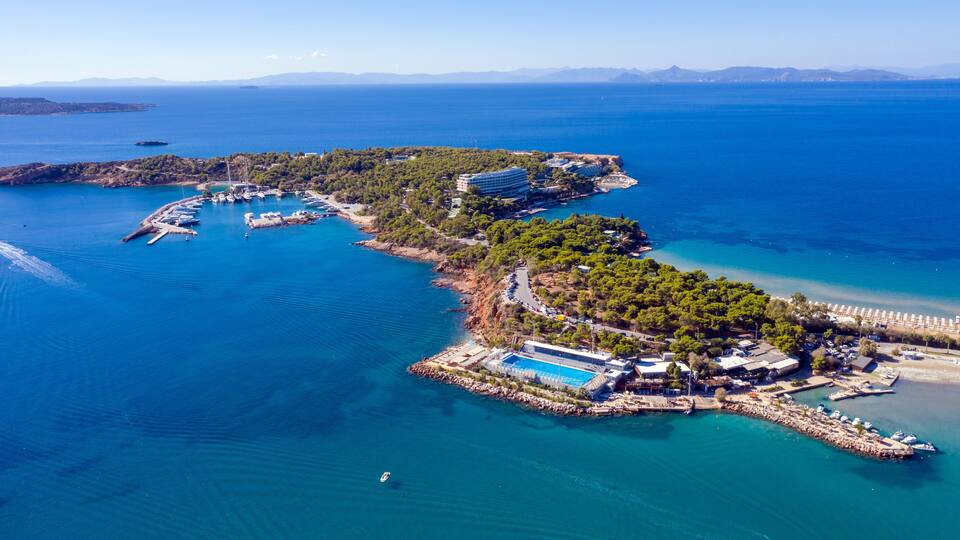 An aerial view of a coastal resort with a marina, swimming pool, and lush greenery.