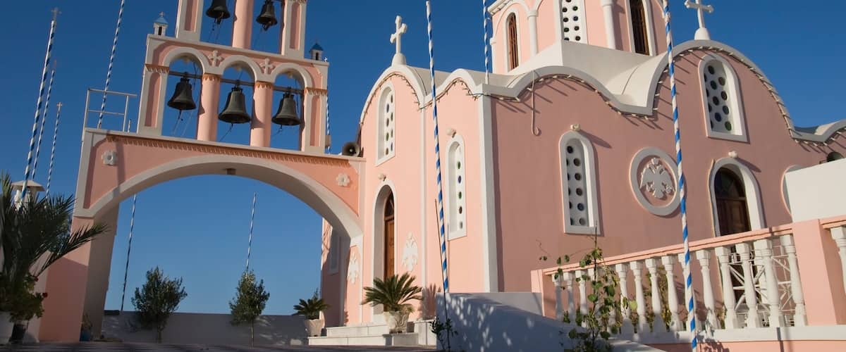 A pink church with a bell tower and a dome.