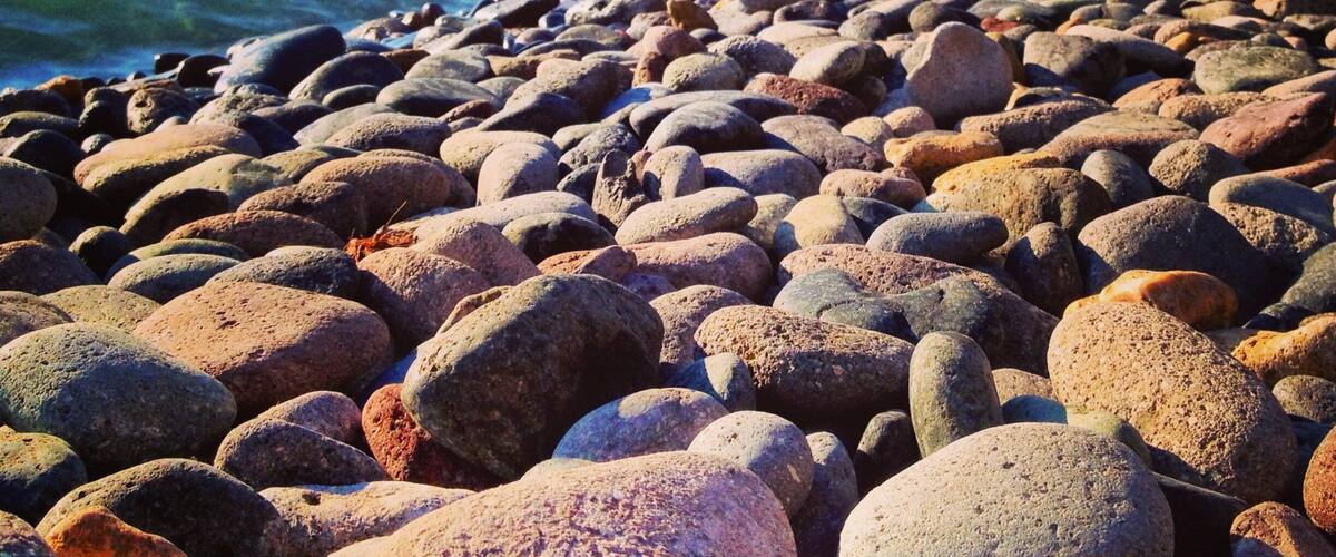 A rocky beach with a town in the background.