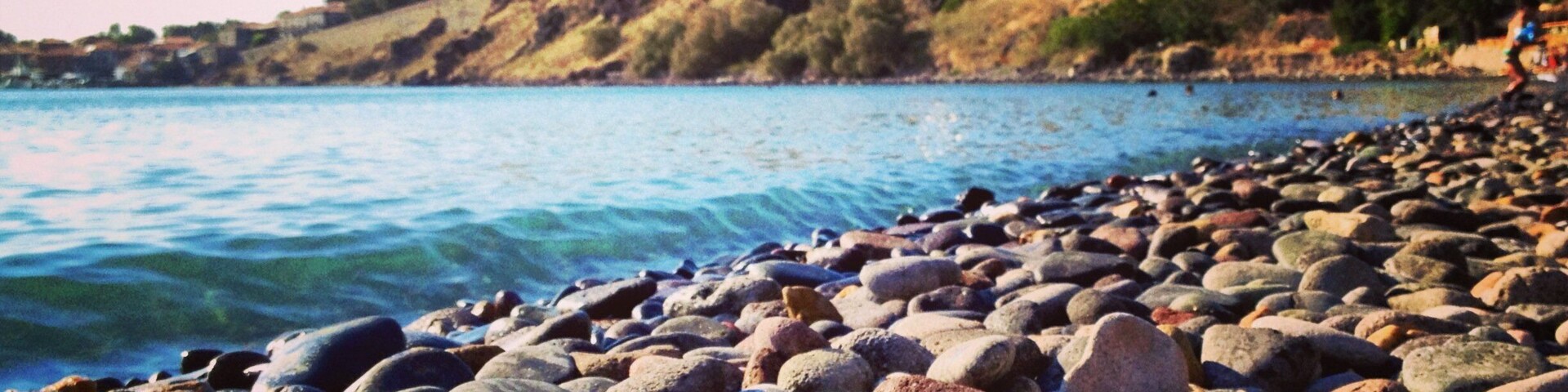 A rocky beach with a town in the background.