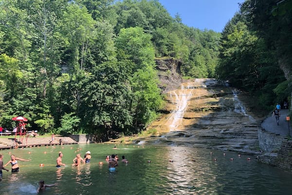 Une cascade se jetant dans un bassin d’eau claire, le tout entouré d’une végétation luxuriante.