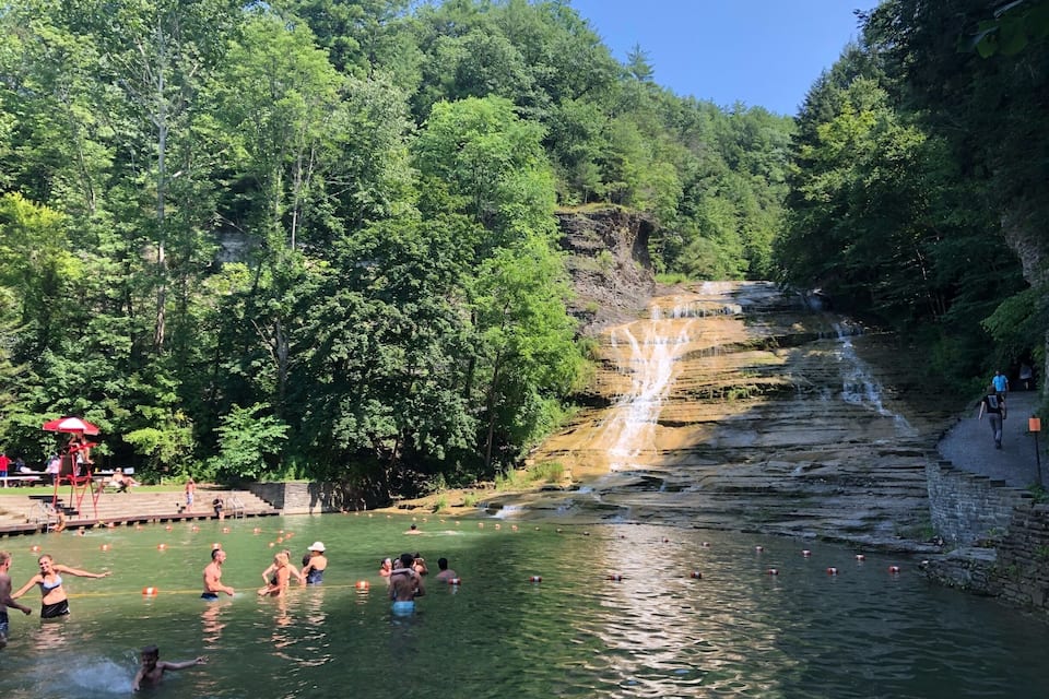 Una cascada que se precipita en una piscina cristalina rodeada de exuberante vegetación.