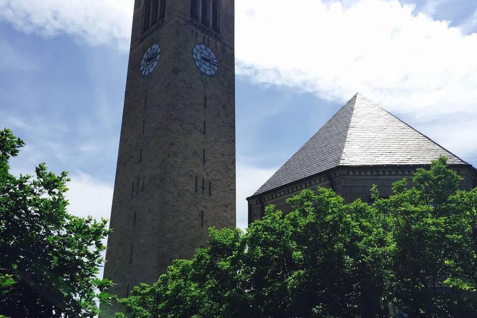 A tall clock tower with a pointed roof and two large clocks.