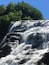 A multi-tiered waterfall surrounded by dense green foliage.