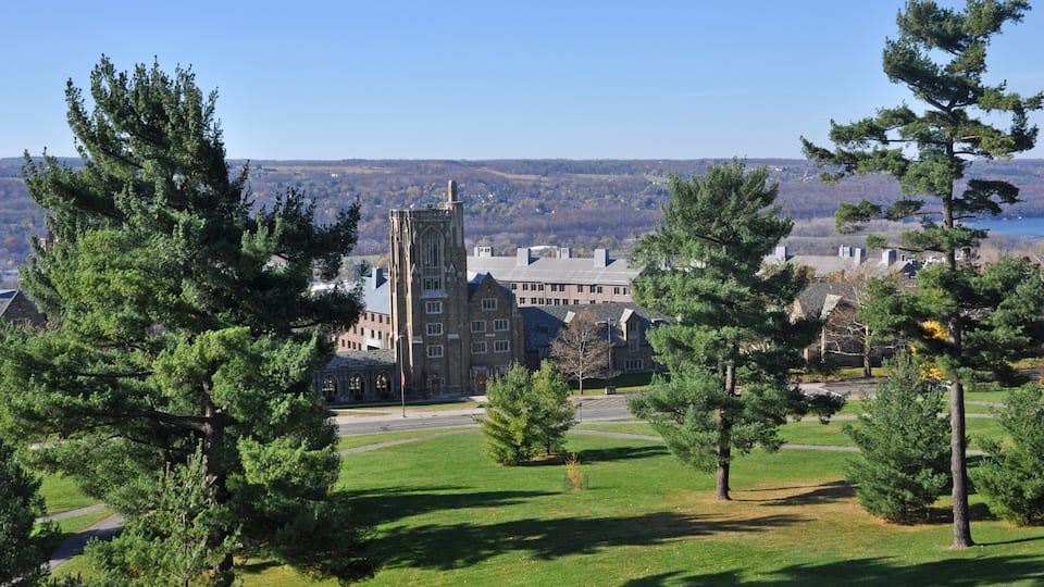 A large building with a prominent tower, surrounded by a grassy area and trees.
