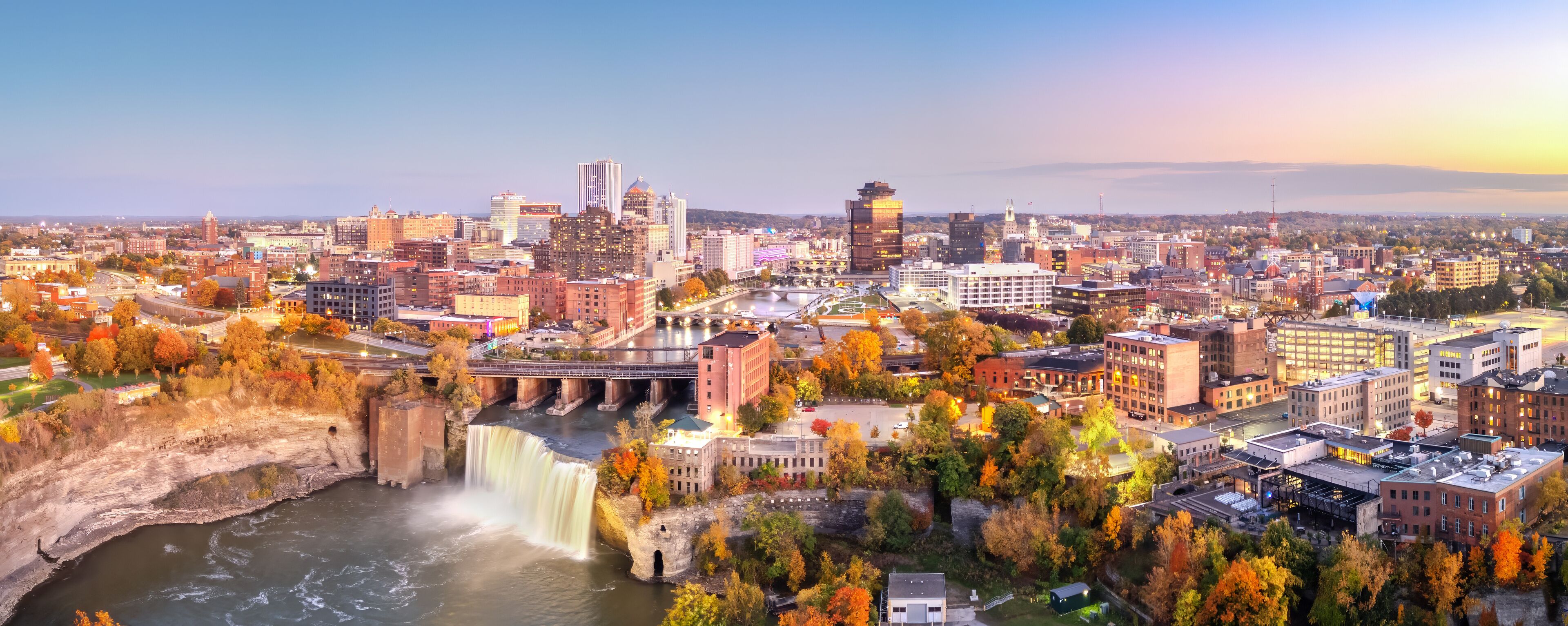 Rochester, New York, USA cityscape on the Genesee River and High Falls at twilight.
