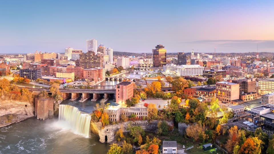 Rochester, New York, USA cityscape on the Genesee River and High Falls at twilight.