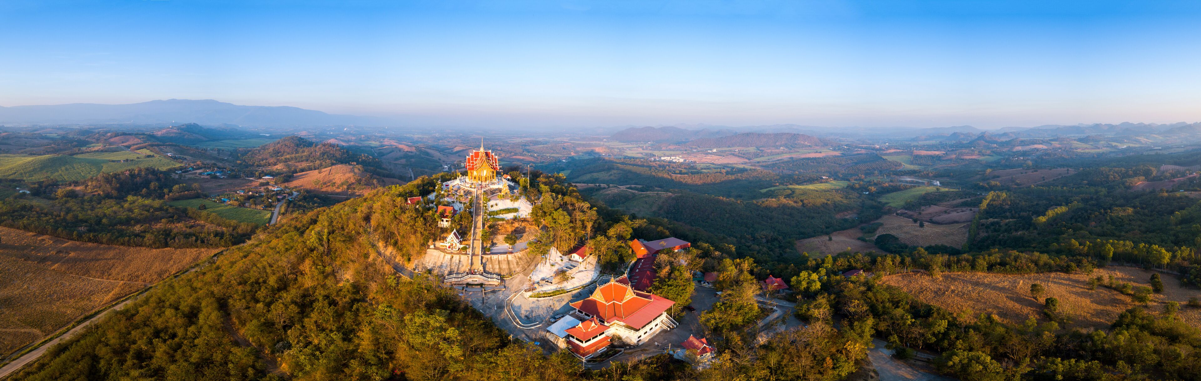 A temple on a hilltop surrounded by forested landscape.