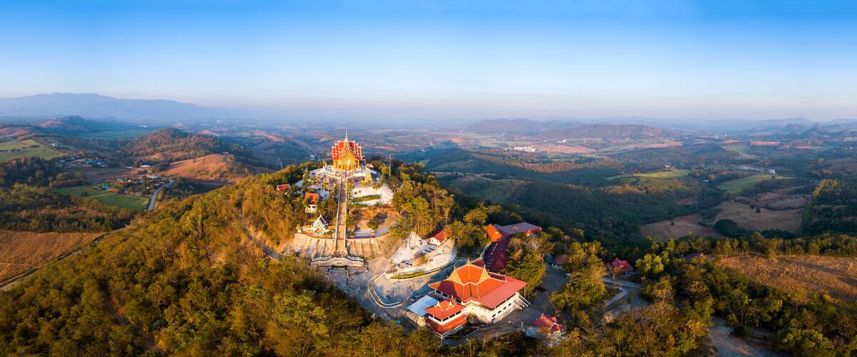 A temple on a hilltop surrounded by forested landscape.