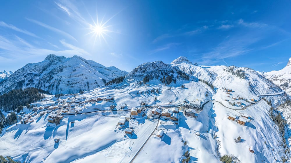 Ein verschneites Bergdorf mit Skipisten und Häusern.