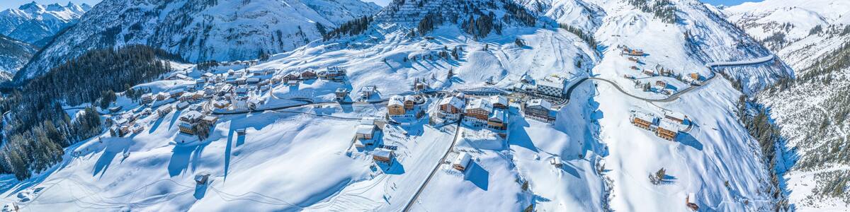 A snow-covered mountain village with ski trails and buildings.