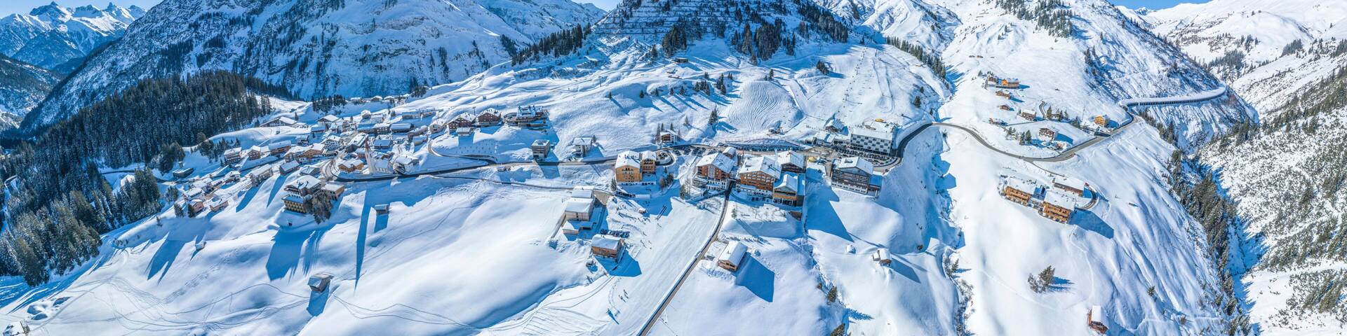 A snow-covered mountain village with ski trails and buildings.