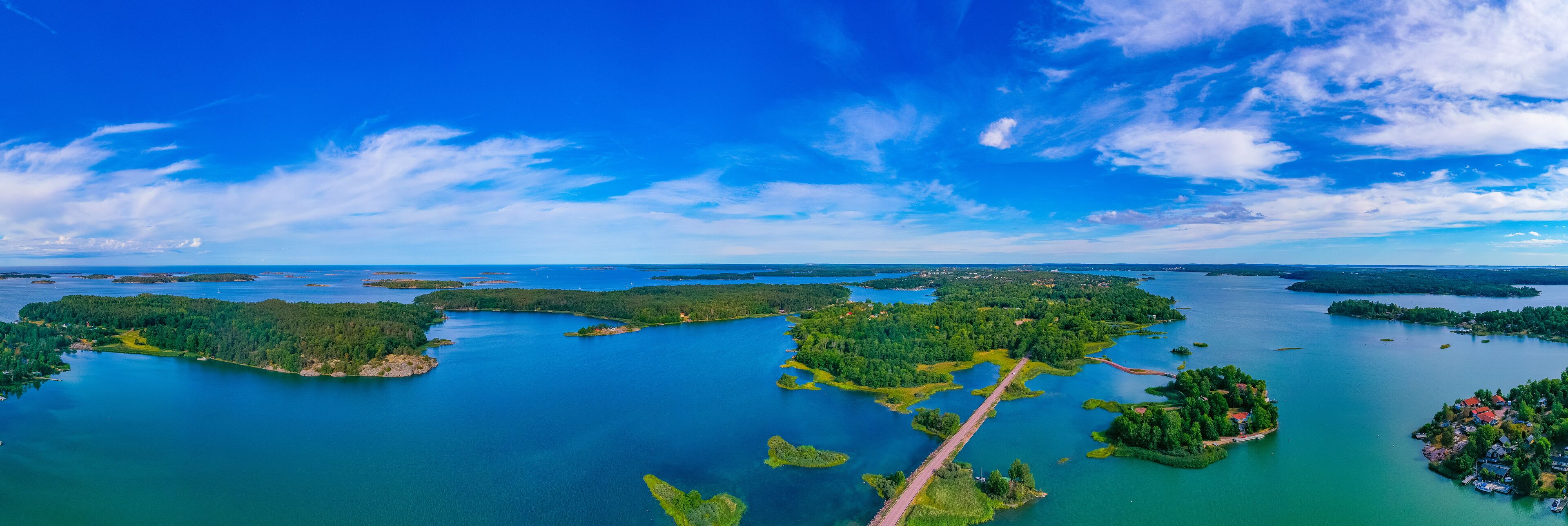 An aerial view of a lake surrounded by forested islands and a bridge.