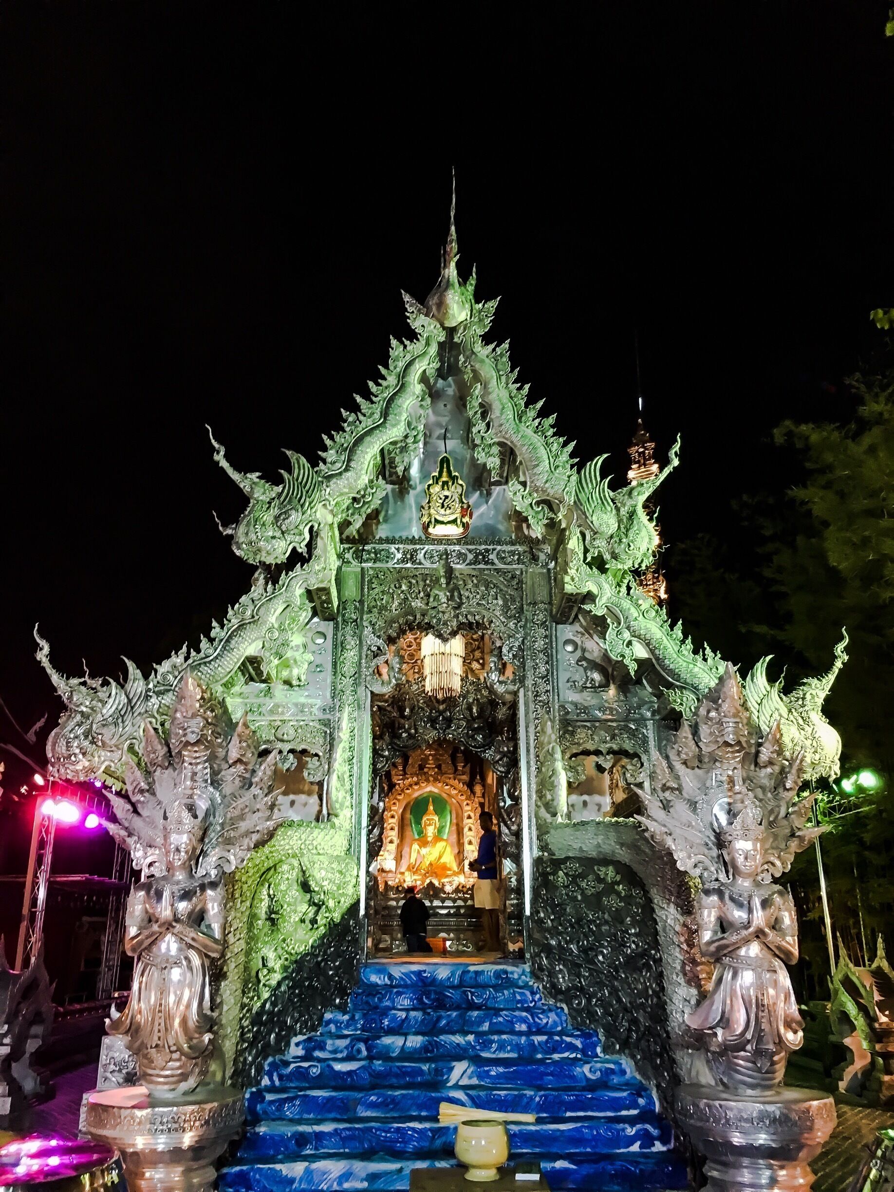 Un tempio con elaborate decorazioni a forma di drago verde e una statua centrale di Buddha.