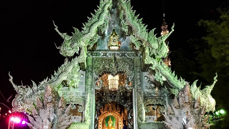 A temple with ornate green dragon decorations and a central Buddha statue.