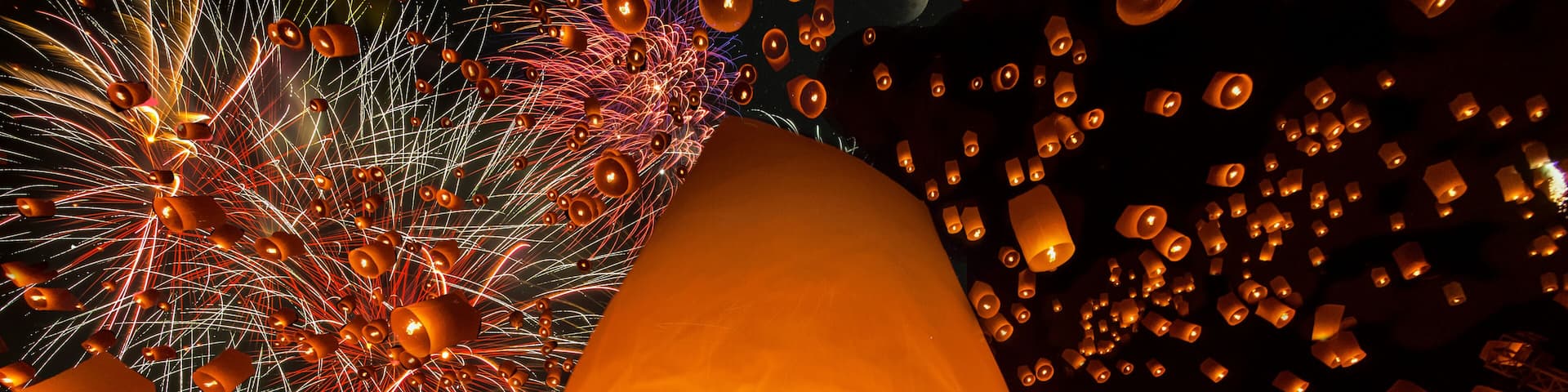 A night sky filled with lanterns and fireworks.