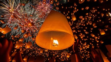 Cielo nocturno lleno de linternas y fuegos artificiales.