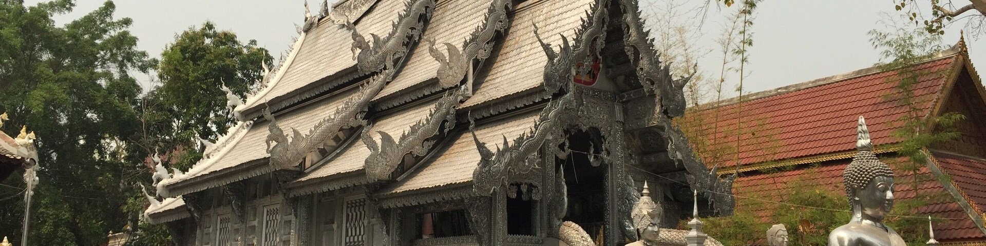 Um templo tradicional tailandês com arquitetura ornamentada, incluindo um telhado em vários níveis e esculturas detalhadas.