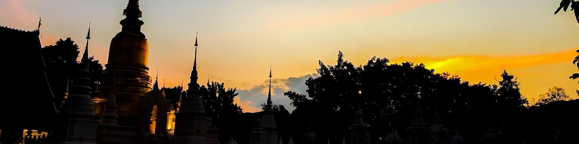 A temple complex with multiple spires silhouetted against a sunset sky.