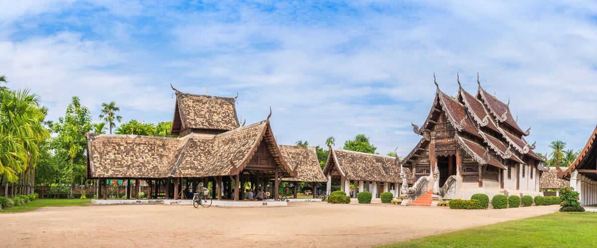 A traditional Thai temple complex with ornate architecture and a well-maintained garden.