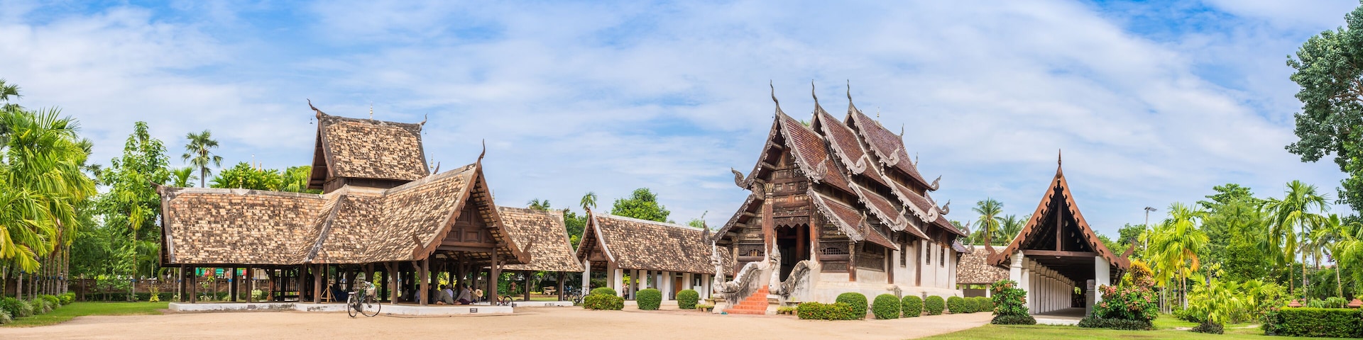 A traditional Thai temple complex with ornate architecture and a well-maintained garden.