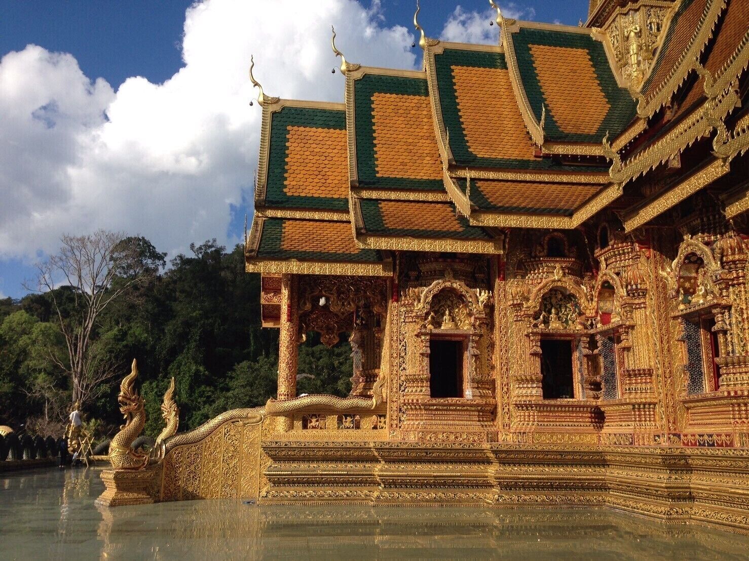 Un templo dorado con intrincadas esculturas y su reflejo en el agua.