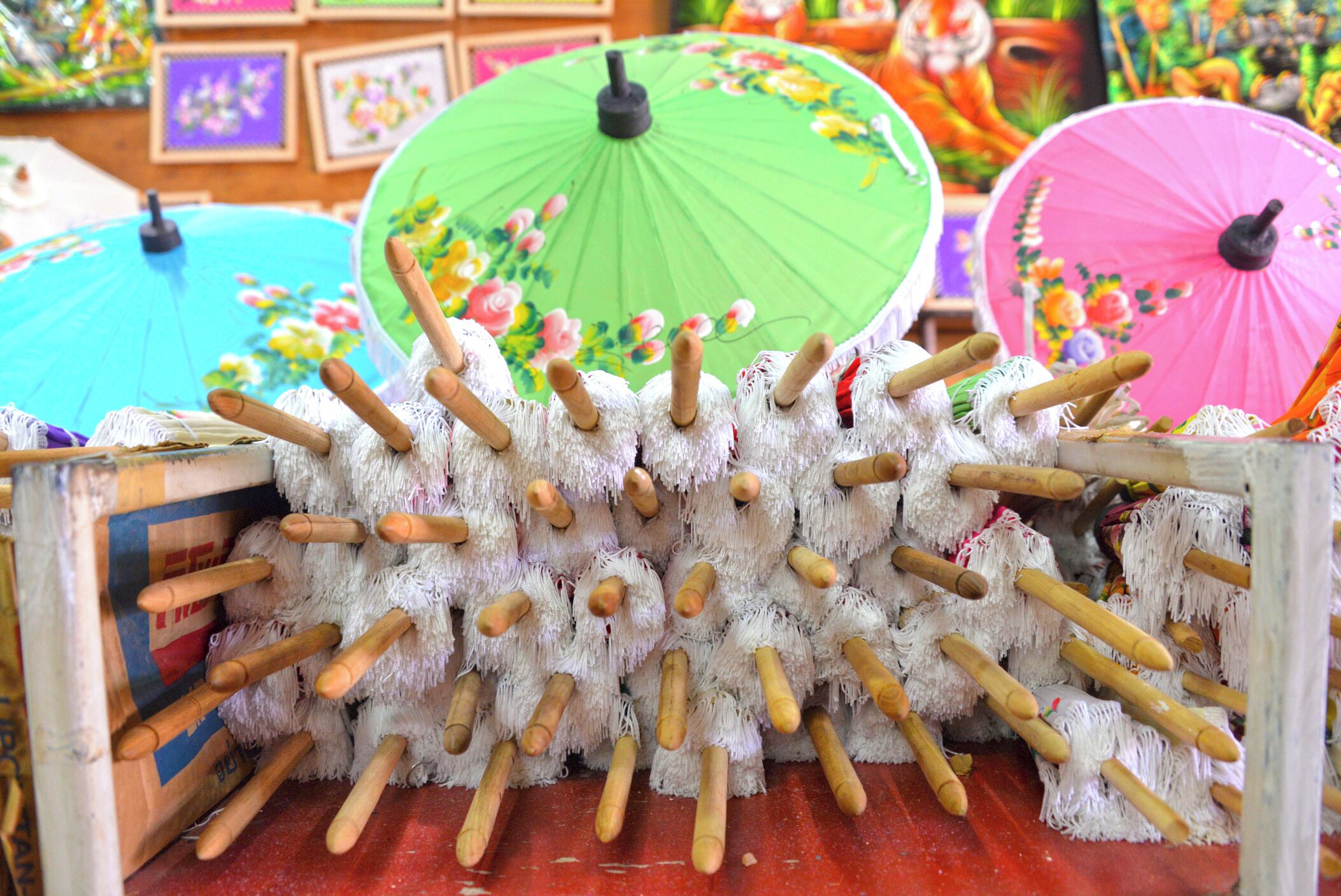 A collection of colorful umbrellas and a pile of white, fluffy objects with wooden handles.