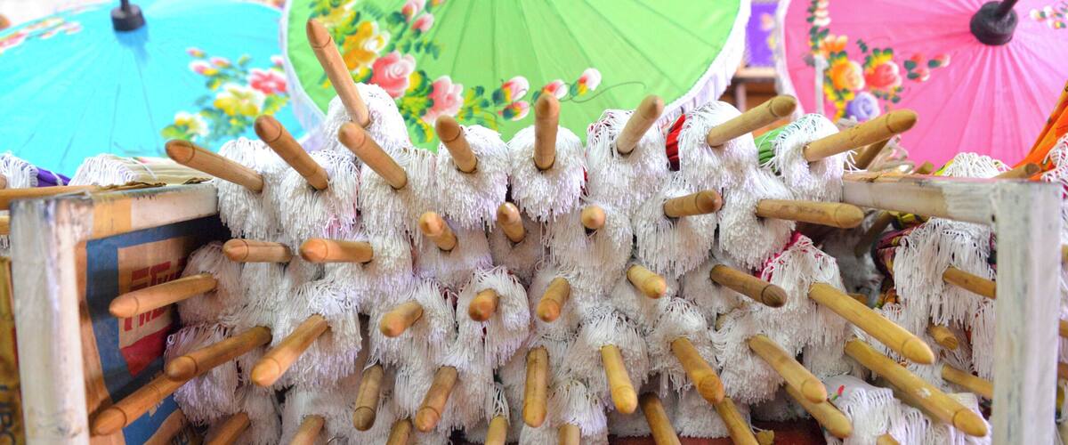 A collection of colorful umbrellas and a pile of white, fluffy objects with wooden handles.