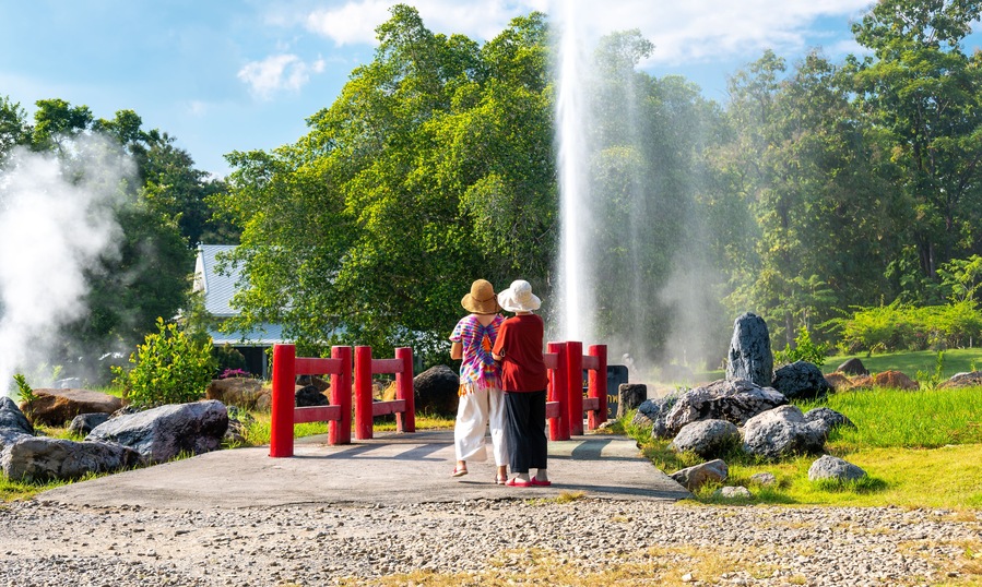 Two unidentifiable people are standing in front of hot spring at San Kamphaeng springs, Thailand.