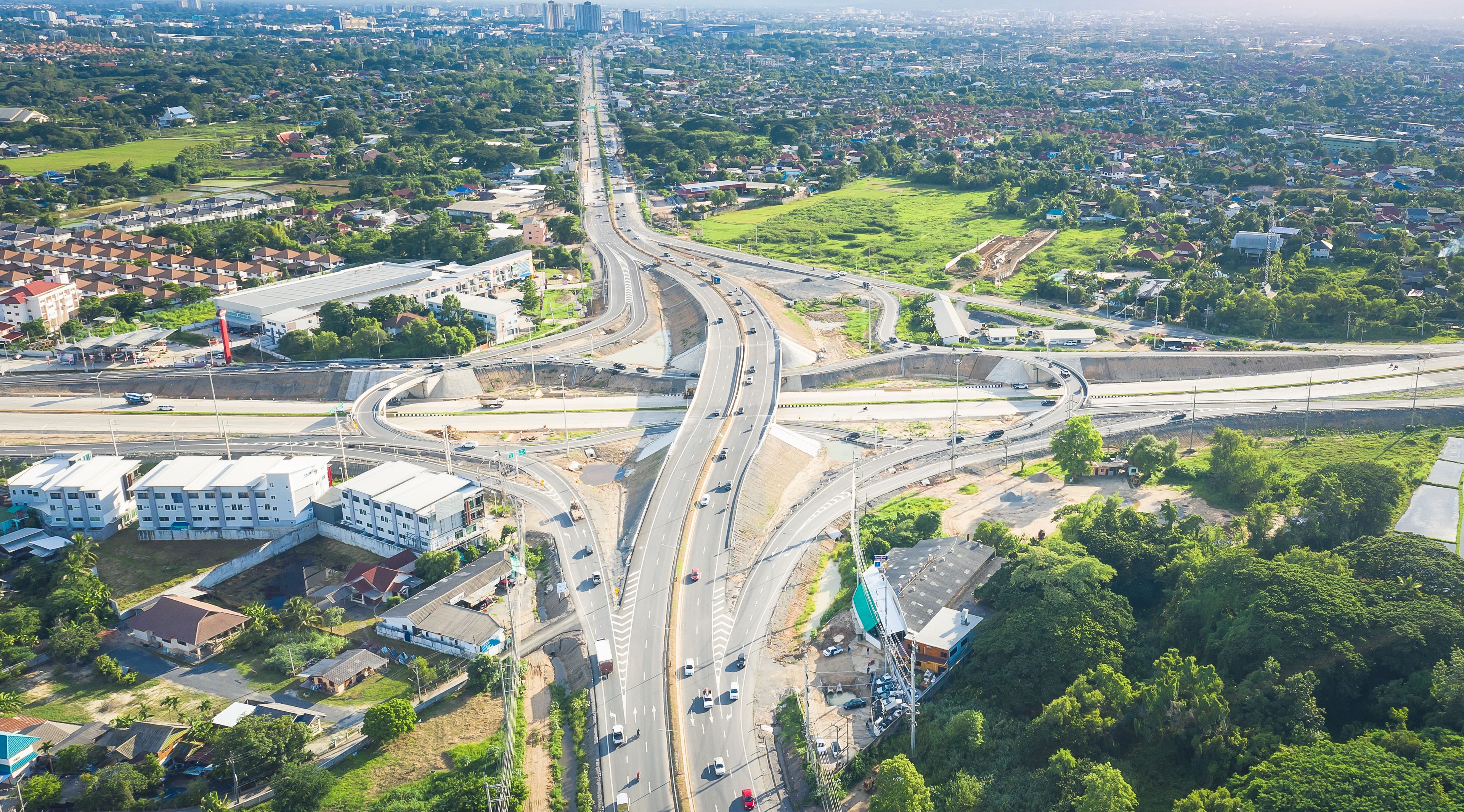 Aerial view of Mae Kuang intersection in San Sai, Chiang Mai, Thailand, with multilane highway, overpass and moving traffic illustrating regional mobility, logistics and road network development.
