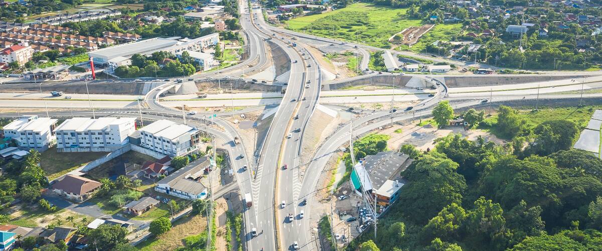 Aerial view of Mae Kuang intersection in San Sai, Chiang Mai, Thailand, with multilane highway, overpass and moving traffic illustrating regional mobility, logistics and road network development.