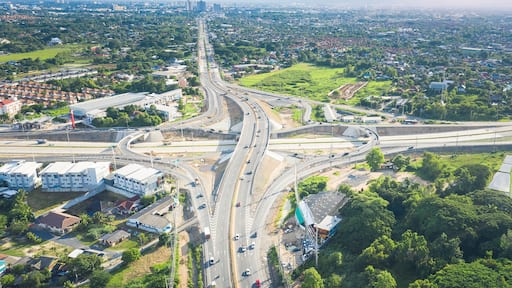 Aerial view of Mae Kuang intersection in San Sai, Chiang Mai, Thailand, with multilane highway, overpass and moving traffic illustrating regional mobility, logistics and road network development.