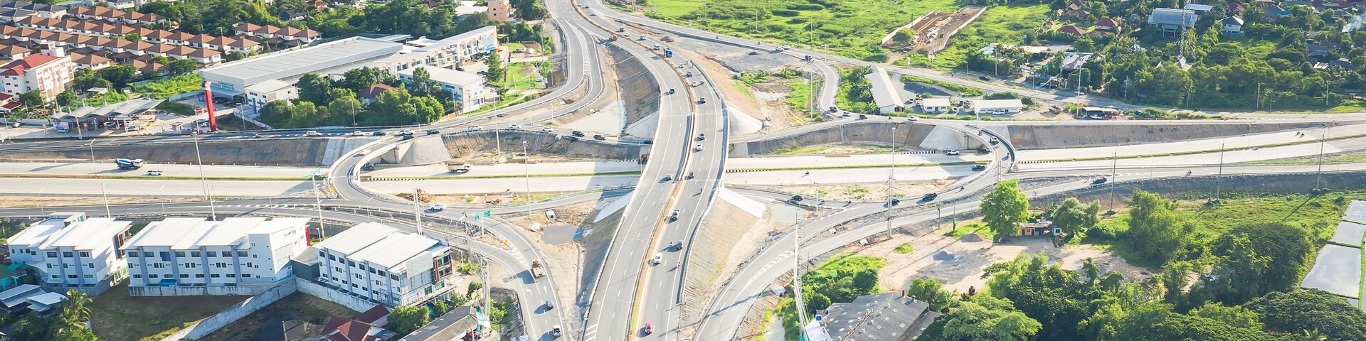 Un cruce de autopistas a varios niveles con zonas residenciales y vegetación circundante.