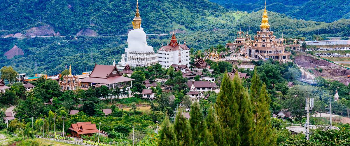 A mountainous landscape with a white temple and a golden pagoda.