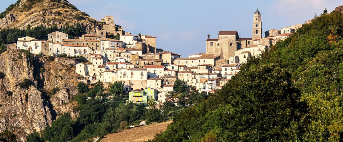 A hillside town with historic buildings, a prominent church, and a rocky mountain backdrop.