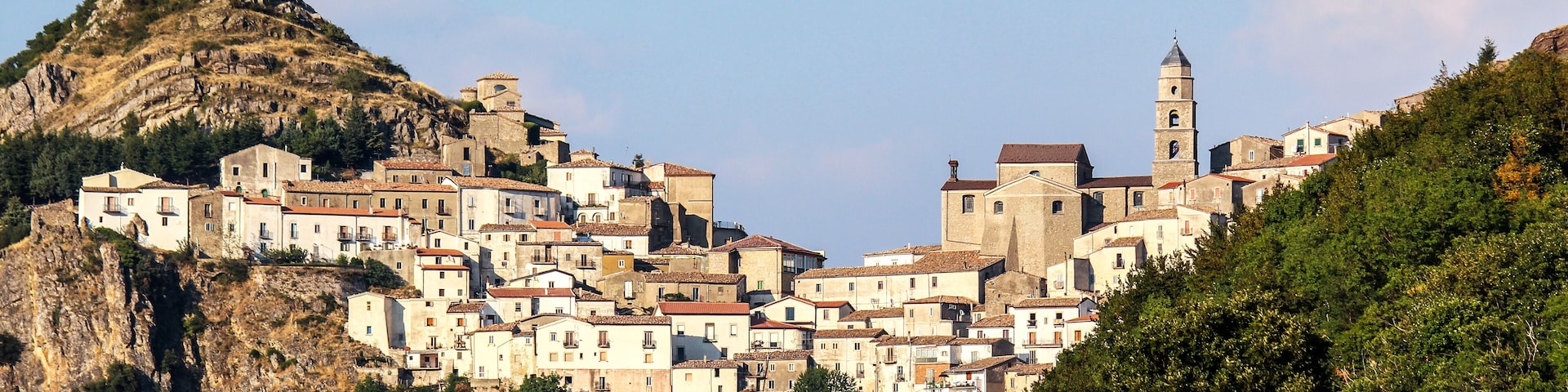 A hillside town with historic buildings, a prominent church, and a rocky mountain backdrop.