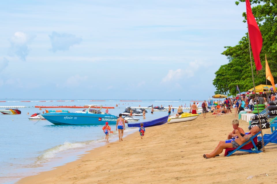Una playa con barcos, gente y sillas de playa.
