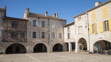 A cobblestone courtyard with stone buildings, half-timbered architecture, and arched doorways.