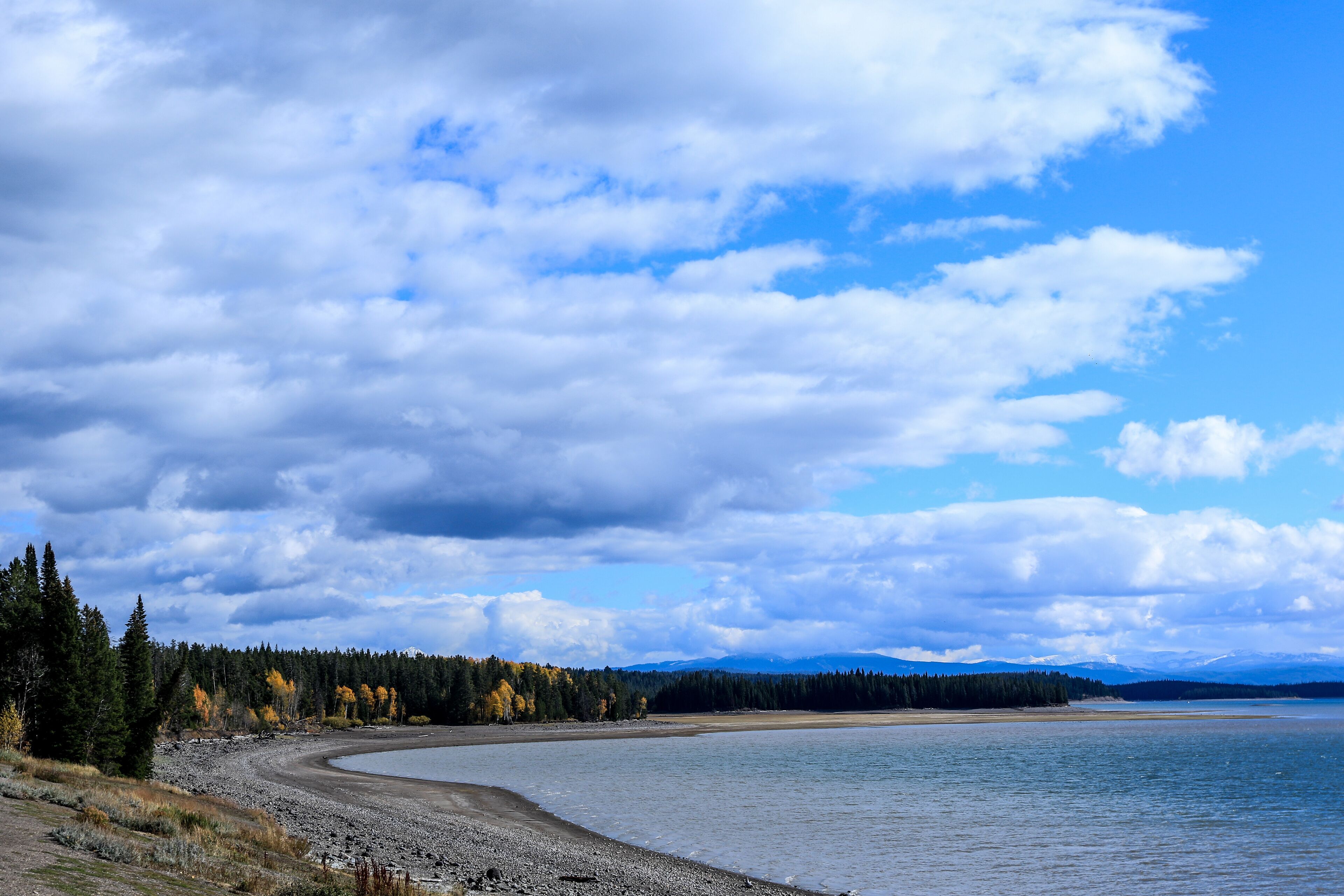 A river curving through a forest with autumn-colored trees and a cloudy sky.