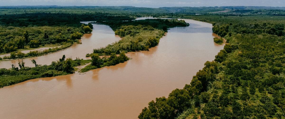 A river winding through a dense green landscape with a cloudy sky.