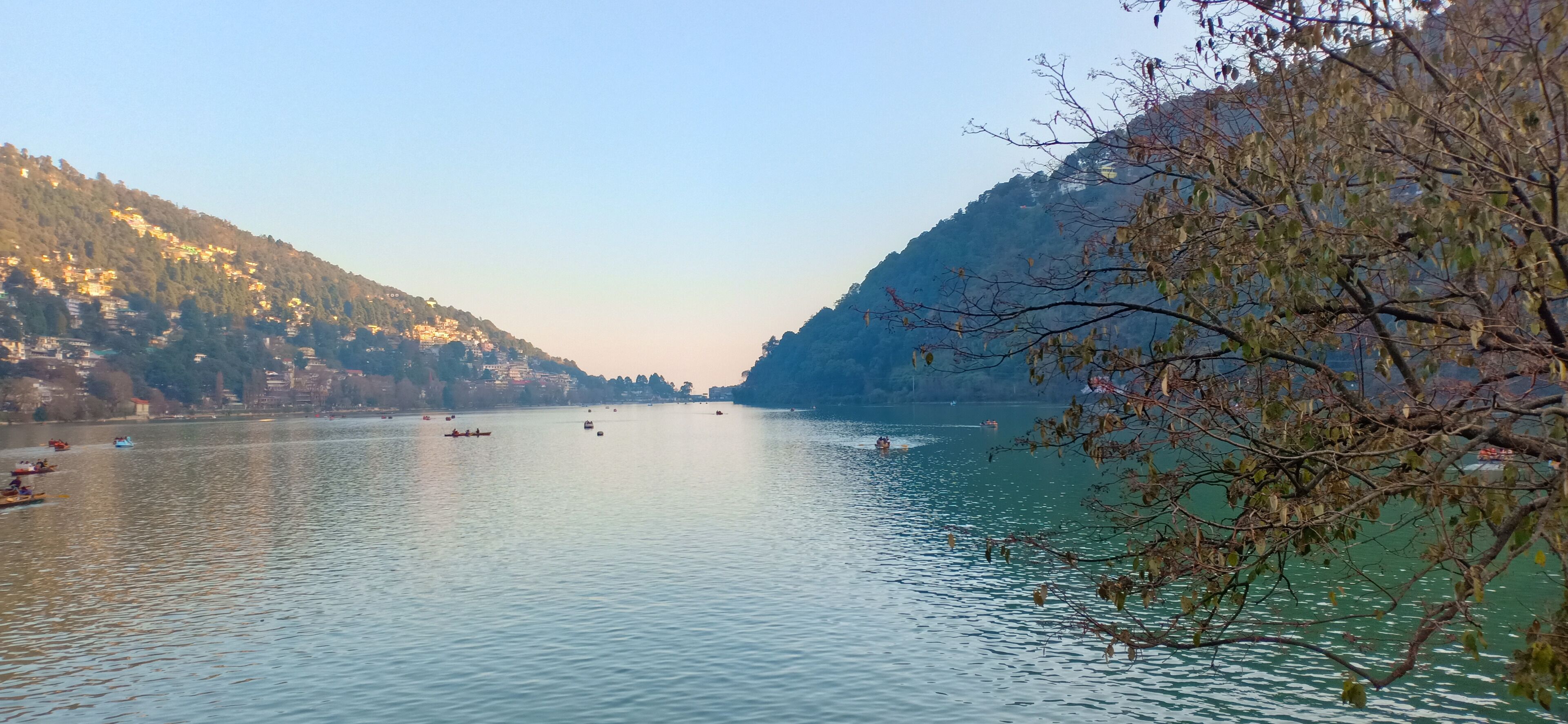 A calm river with boats, surrounded by hills and sparse trees.