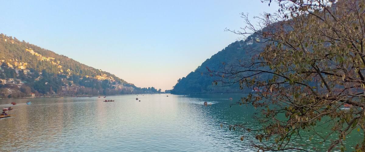A calm river with boats, surrounded by hills and sparse trees.